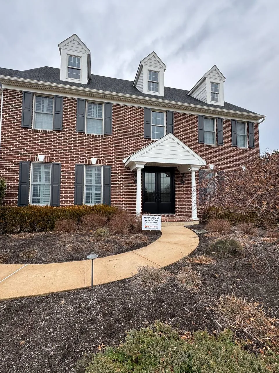 Windows and entry door: Brick colonial, black entry door. Installed by HomeTrust Windows & Doors.